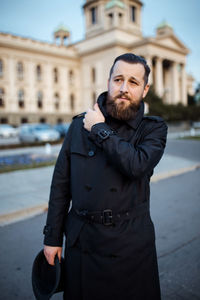 Portrait of young man standing against built structure