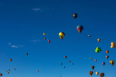 Low angle view of hot air balloons flying against blue sky