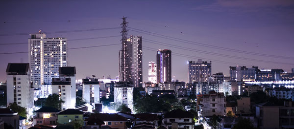 Illuminated cityscape against sky at dusk