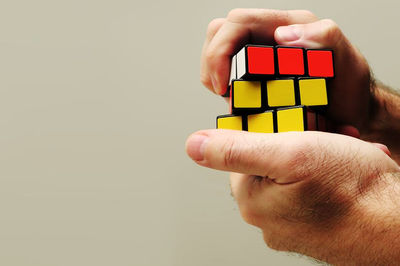 Close-up of hand holding toy against white background