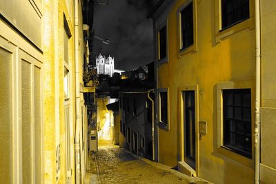 Narrow street amidst buildings in city at night