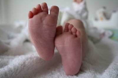 Low section of baby lying on bed at home