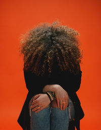 Midsection of woman standing against orange wall