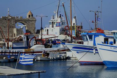 Greek flag against boats moored at harbor