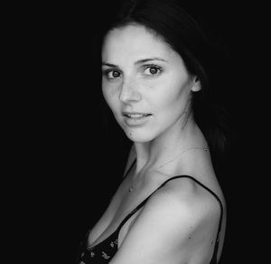 Close-up portrait of woman against black background