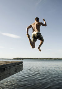 Full length of mature man jumping into sea