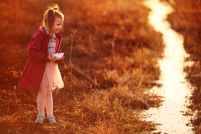 Girl in the spring on the creek launches paper boats