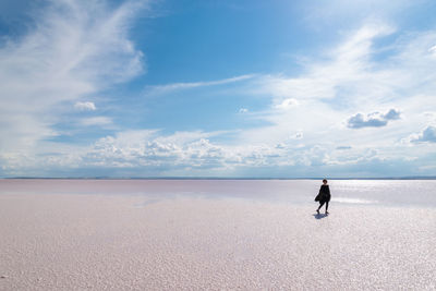 Woman walking on beach against sky