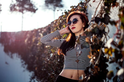 Fashionable woman wearing sunglasses while standing by wall