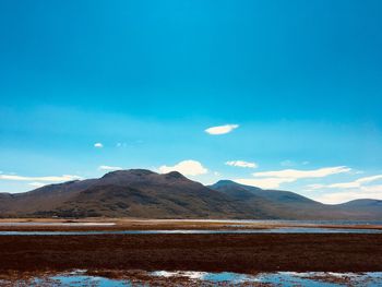 Scenic view of sea and mountains against blue sky