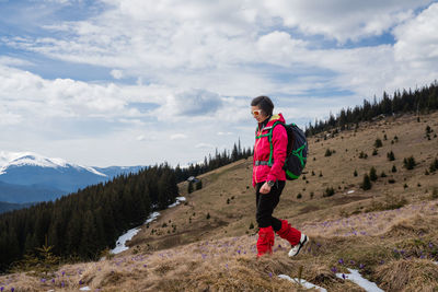 Rear view of man standing on mountain against sky