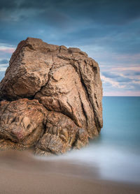 Rock formation at beach against sky