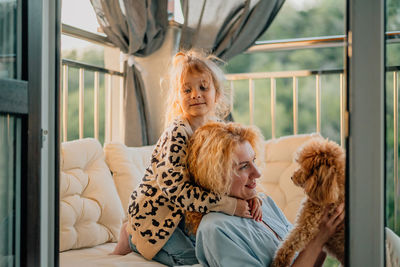 Daughter with mother holding dog at home