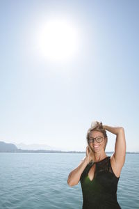 Portrait of smiling woman standing against clear sky