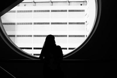 Rear view of woman looking through window