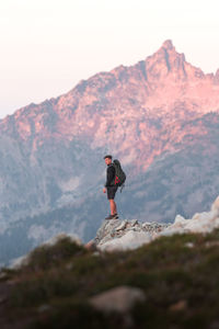 Man standing on rock by mountain against sky
