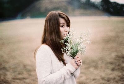 Young woman smelling flowers on field