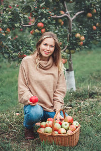 Portrait of smiling pregnant woman picking apples on field