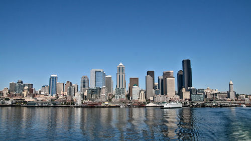 City at waterfront against blue sky