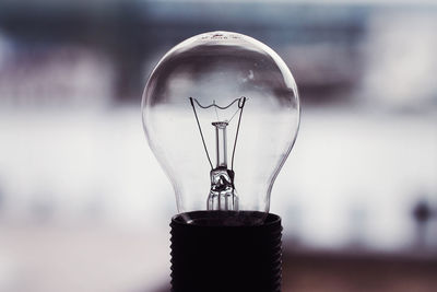 Close-up of illuminated light bulb against wall