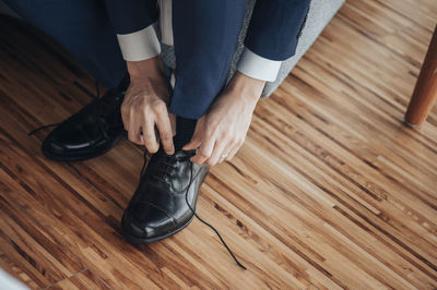 Low section of man tying shoelace