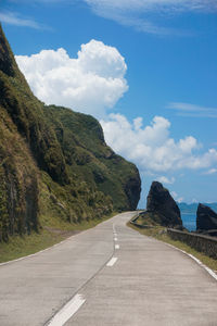 Empty road along landscape against sky