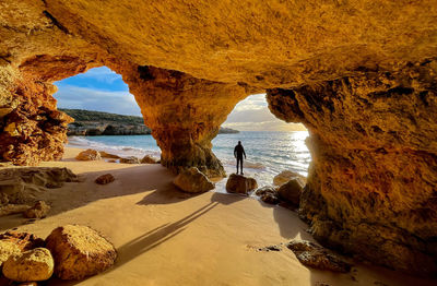 Men in a cave looking at the sunset in algarve portugal