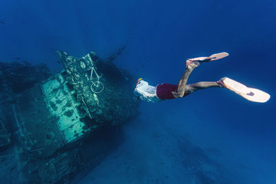 Man swimming towards damaged ship undersea