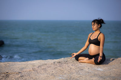 Full length of young woman relaxing on shore