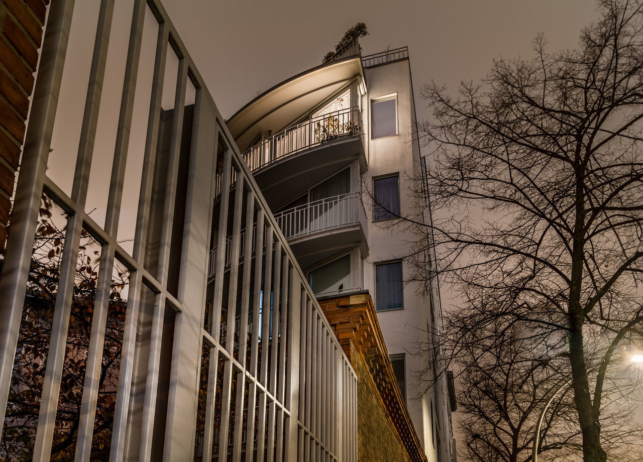 LOW ANGLE VIEW OF BUILDING AND BARE TREES AGAINST SKY