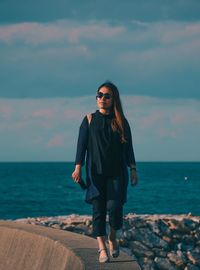 Full length of young woman by sea against sky