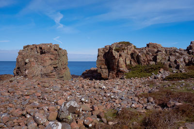 Scenic view of cliff by sea against sky