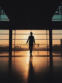 Full length of silhouette boy walking in airport during sunset