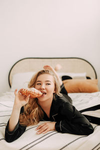 Portrait of a smiling young woman lying on bed