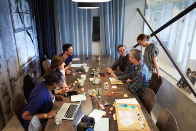 High angle view of colleagues discussing at conference table during meeting in office