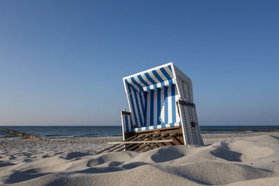 Lifeguard hut on beach against clear blue sky