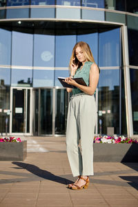 Woman using smart phone while standing on mobile