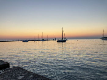 Sailboat sailing on sea against clear sky during sunset