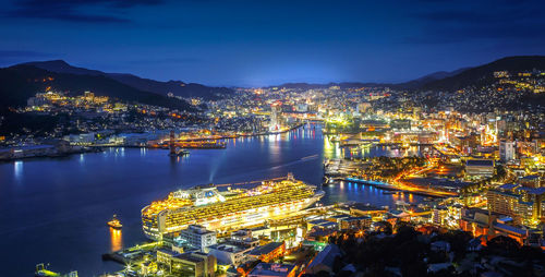 High angle view of illuminated city by river against sky