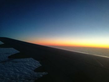 Airplane wing against sky during sunset