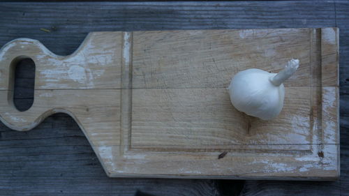 High angle view of garlic on wooden cutting board on wooden table