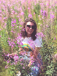 Portrait of smiling young woman against purple flowering plants
