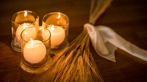 Close-up of lit tea light candles by grains on table