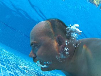 Shirtless man swimming in pool