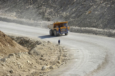 High angle view of construction vehicle moving on road by hill