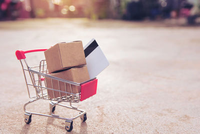 Close-up of cardboard boxes and credit card in miniature shopping cart