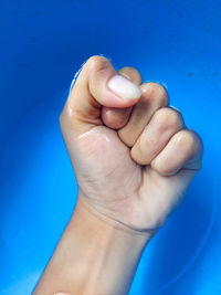 Close-up of person hand against blue background