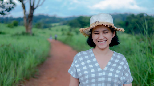 Portrait of a smiling young woman standing on field
