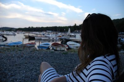 Woman sitting at beach against sky