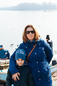 Portrait of woman in sunglasses with son against lake